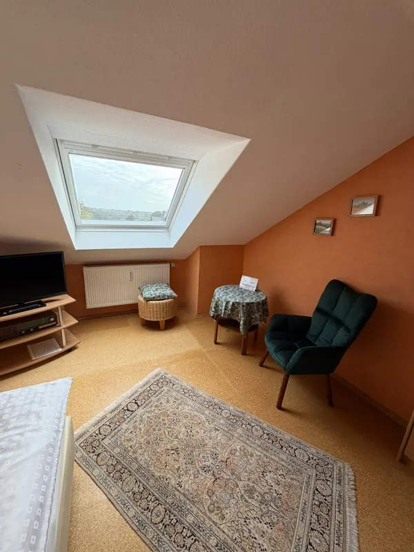 Einzelzimmer mit Sitzecke unter dem Dachfenster